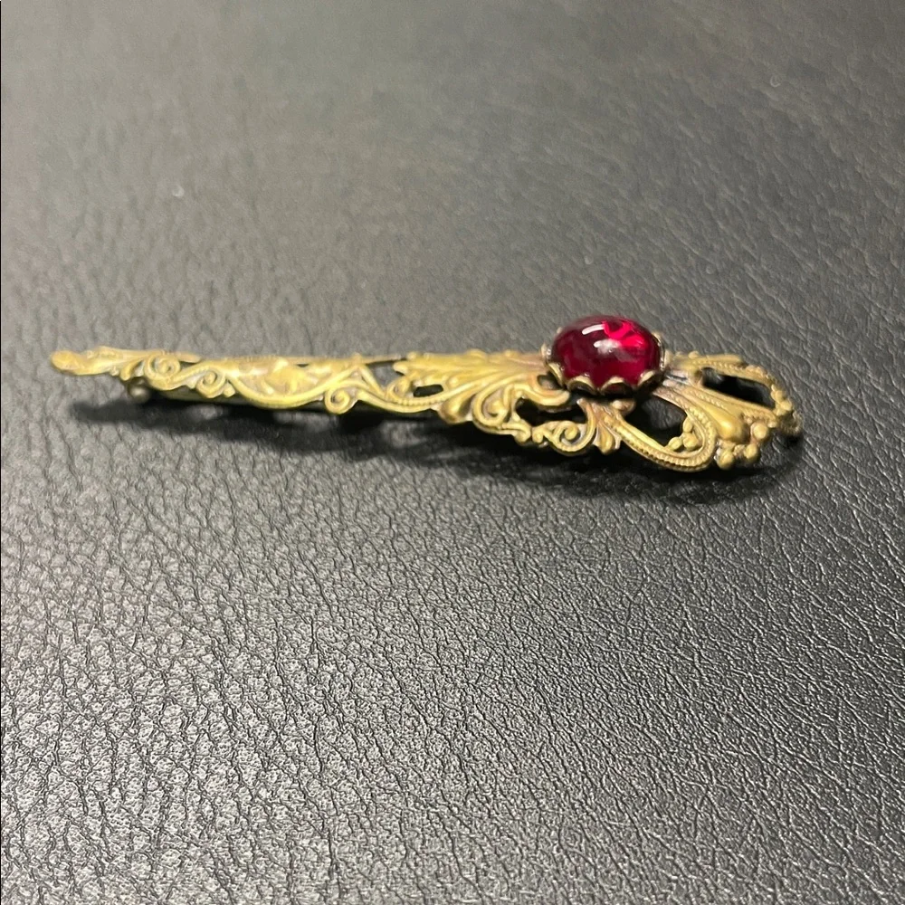 Filigree gold toned, brooch pin with red stone